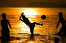 Young boys play soccer as the sunsets
